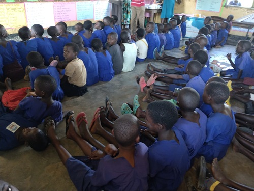 Primary two three children sit on the floor during a lesson